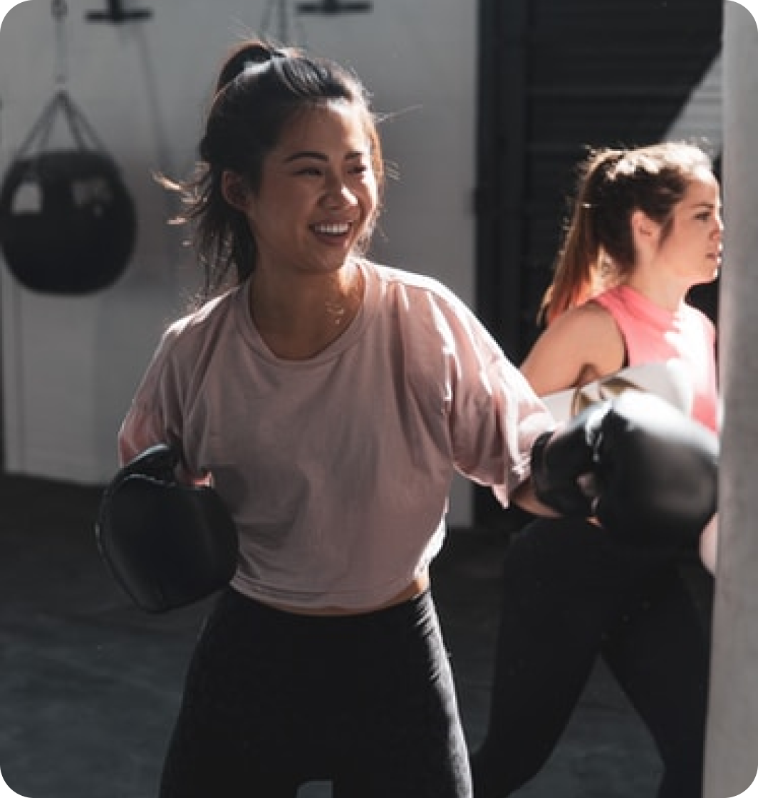 Jeune femme de face faisant de la boxe avec un sac de frappe